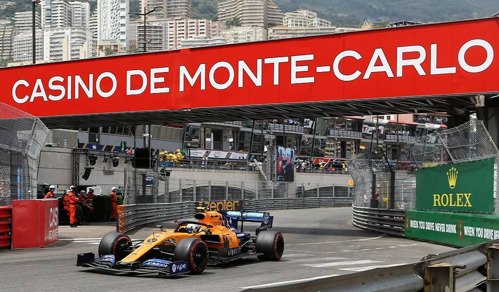 Vista panorámica del Circuito de Mónaco con un coche de F1 pasando por la zona del puerto y los yates.
